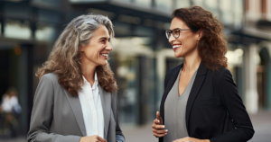 2 ladies dressed in professional attire smiling and having a conversation