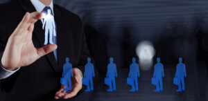 Talent acquisition specialist hand selecting human icon with silhouetted figures